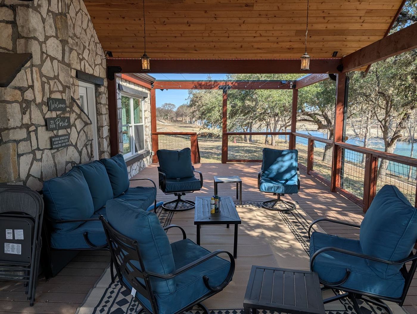 Covered stone porch at The River House with blue patio seating and a view of the river